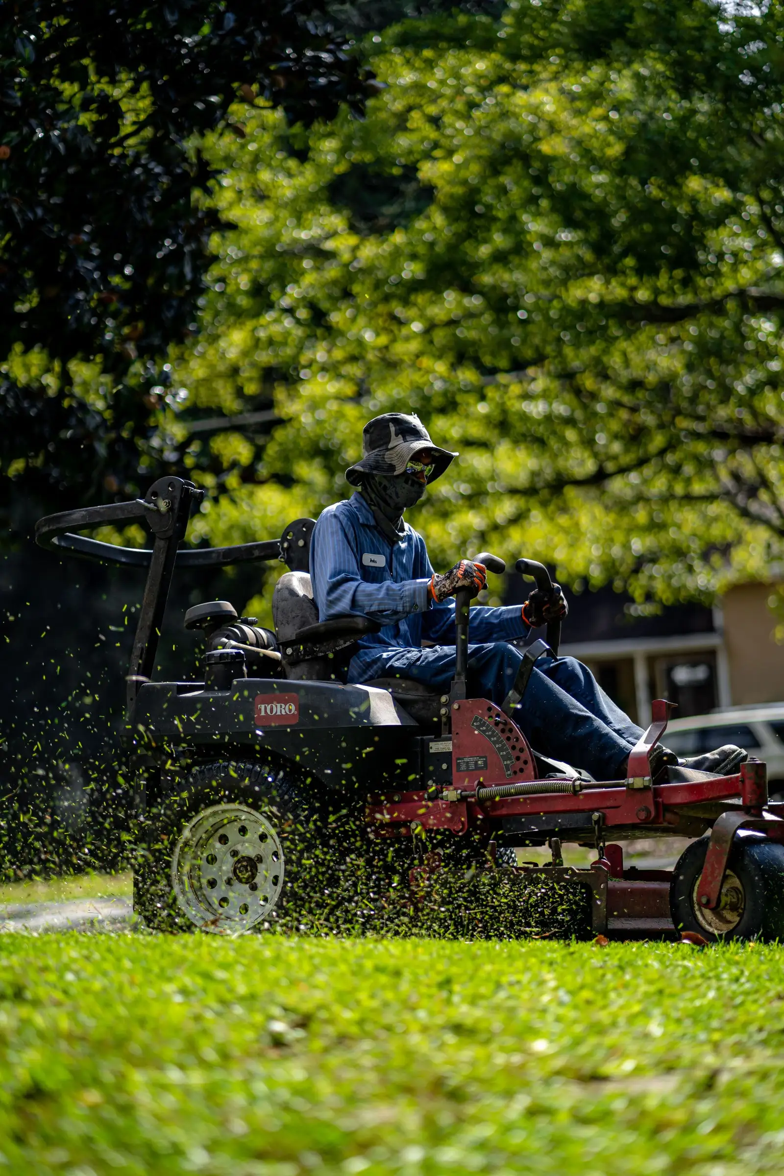 A Tiger Lawn & Landscape crew member mowing a yard on a riding mower