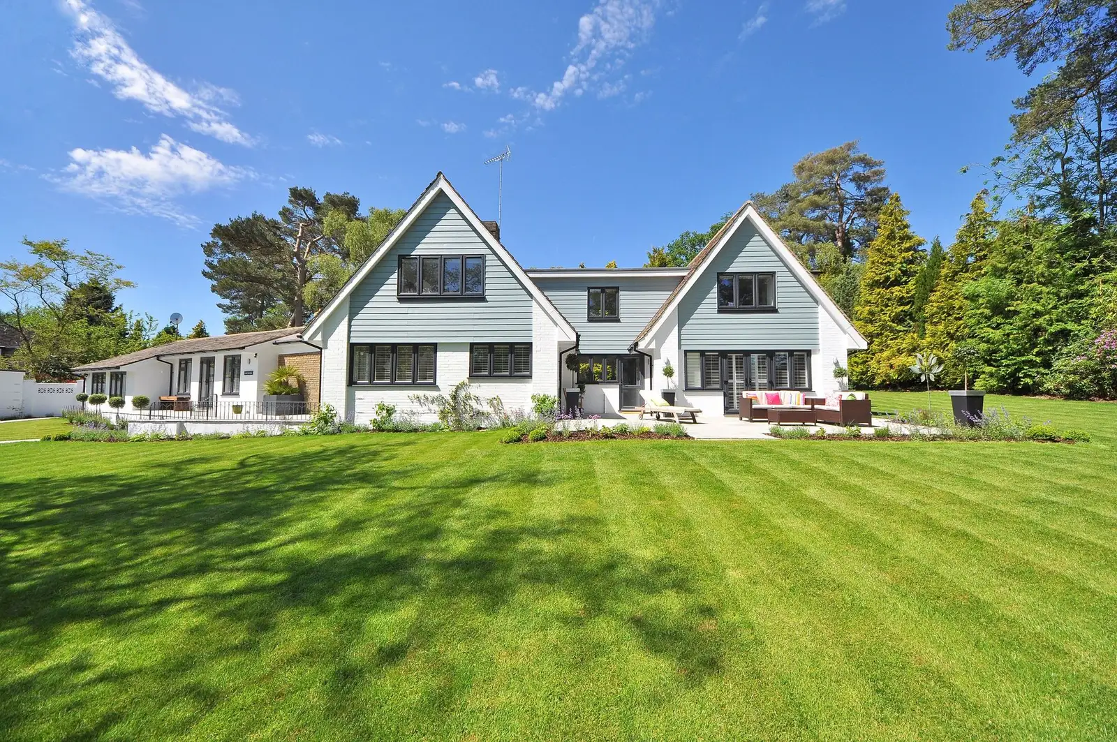 A modern home behind a freshly mowed, neatly striped green lawn
