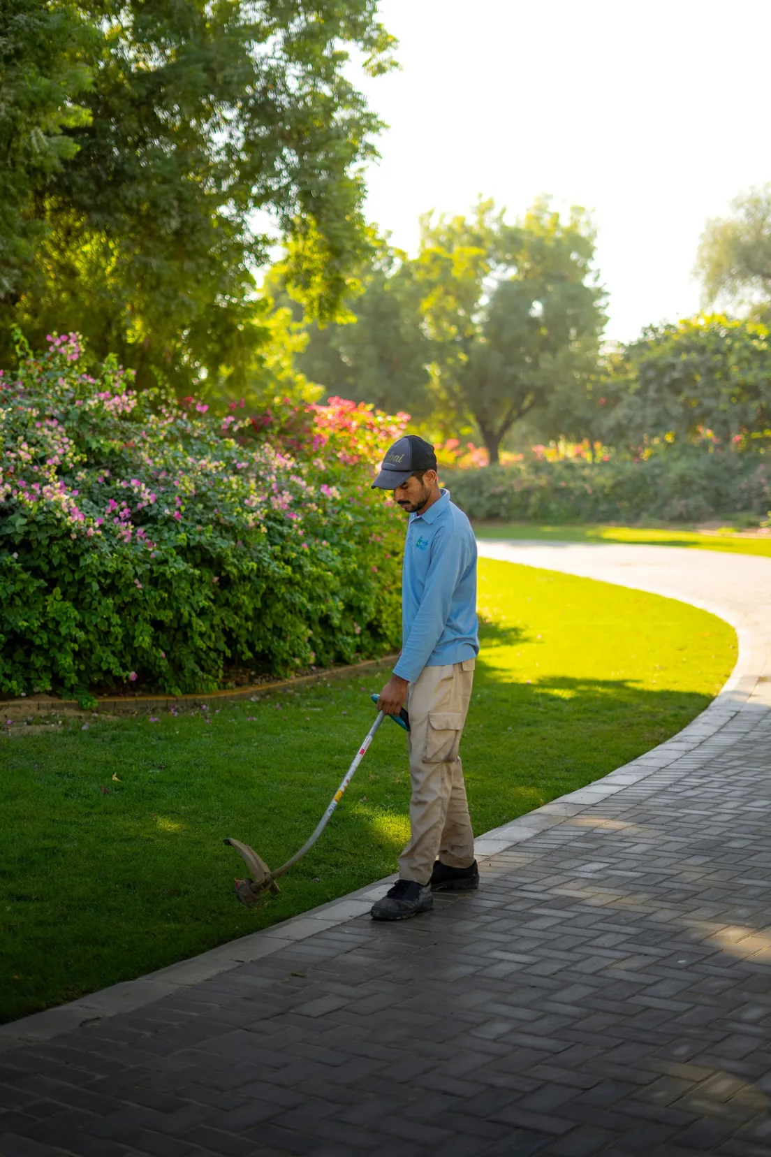 A crew member trimming a lawn edge with a string trimmer